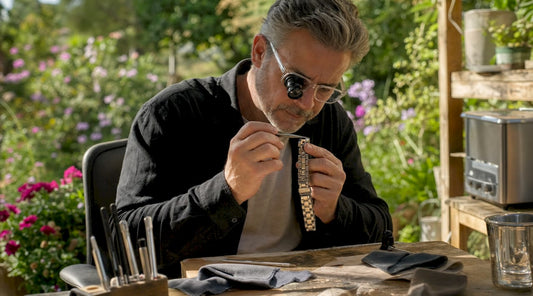 Watchmaker inspecting stainless steel bracelet under loupe