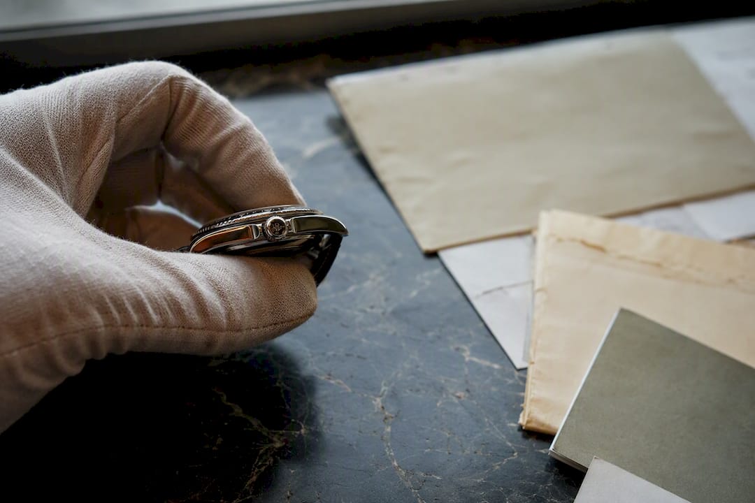 Gloved hand holding luxury watch with documents